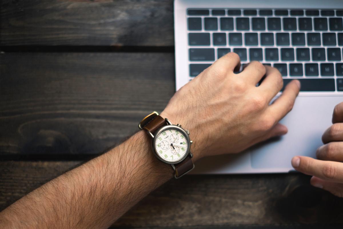 Zeitbasiertes Veröffentlichen Macbook-Benutzer schaut auf seine Uhr